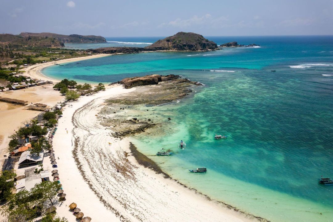 Garis pantai Tanjung Aan dengan pasir putih dan air laut jernih untuk wisata pantai di Lombok