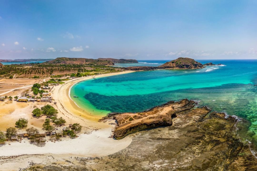 Pemandangan laut biru dan garis pantai Tanjung Aan sebagai destinasi wisata Lombok Selatan