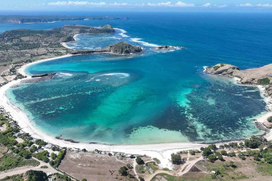 Panorama teluk Tanjung Aan dengan garis pantai melengkung dan perbukitan di Lombok Tengah