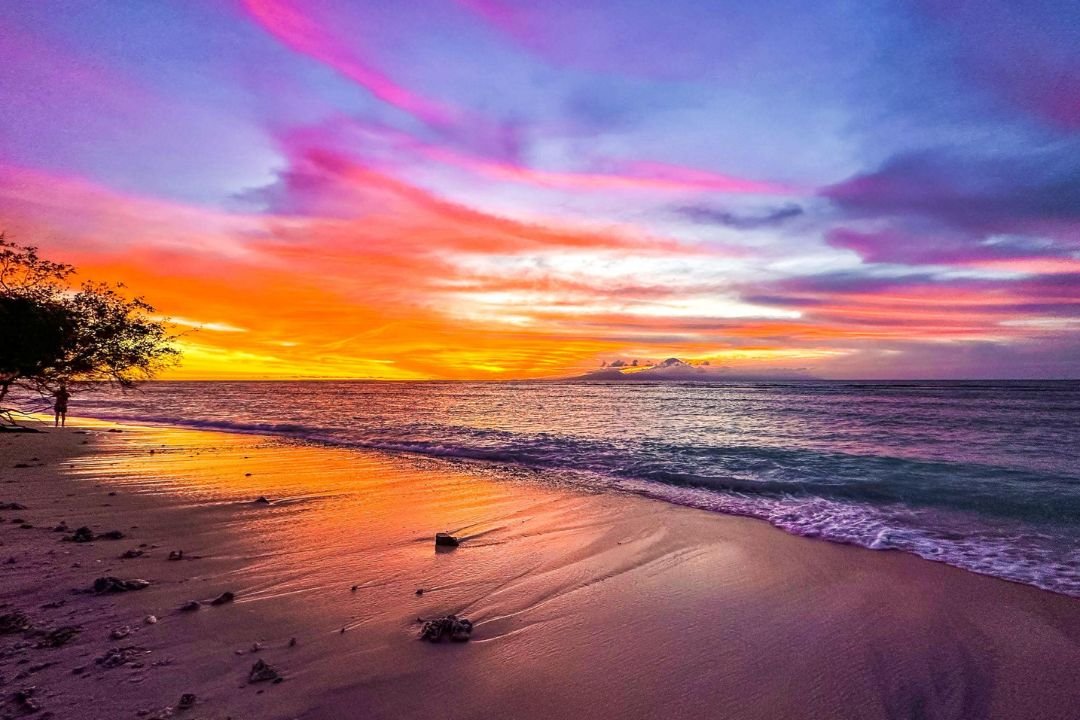Panorama matahari terbenam dengan langit jingga dan laut di pantai Gili Trawangan.